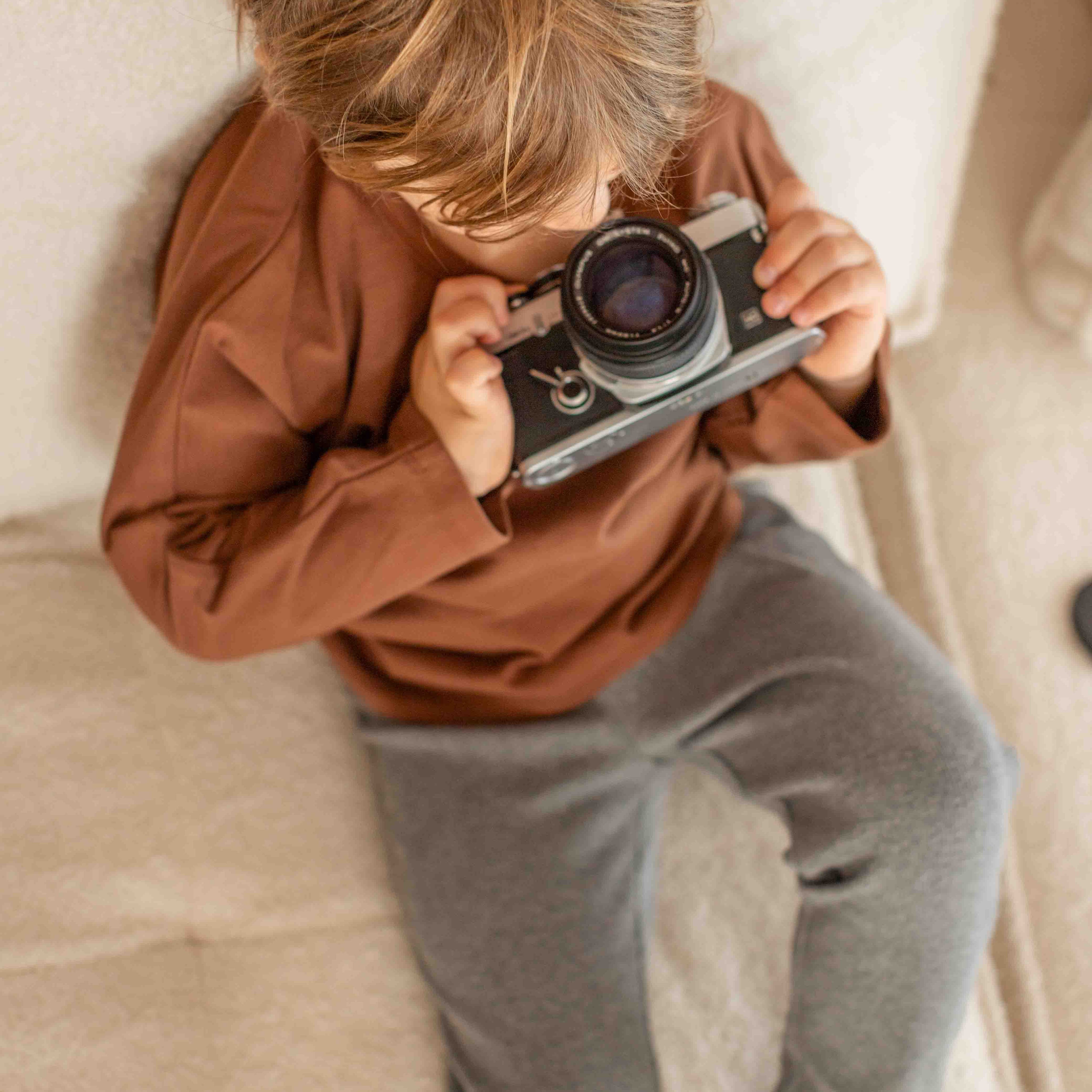 Child holding a vintage camera on a textured surface