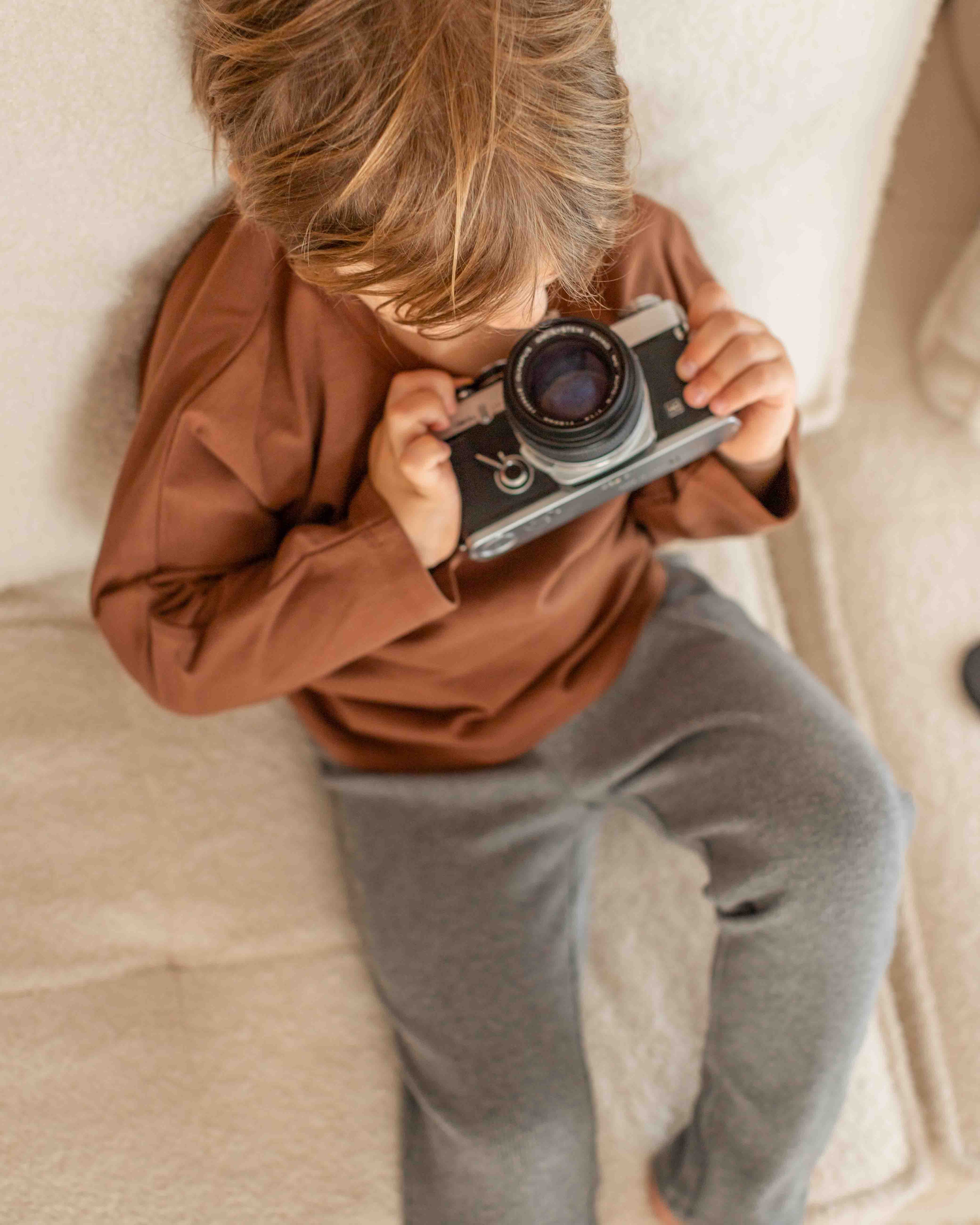 Child holding a vintage camera on a textured surface
