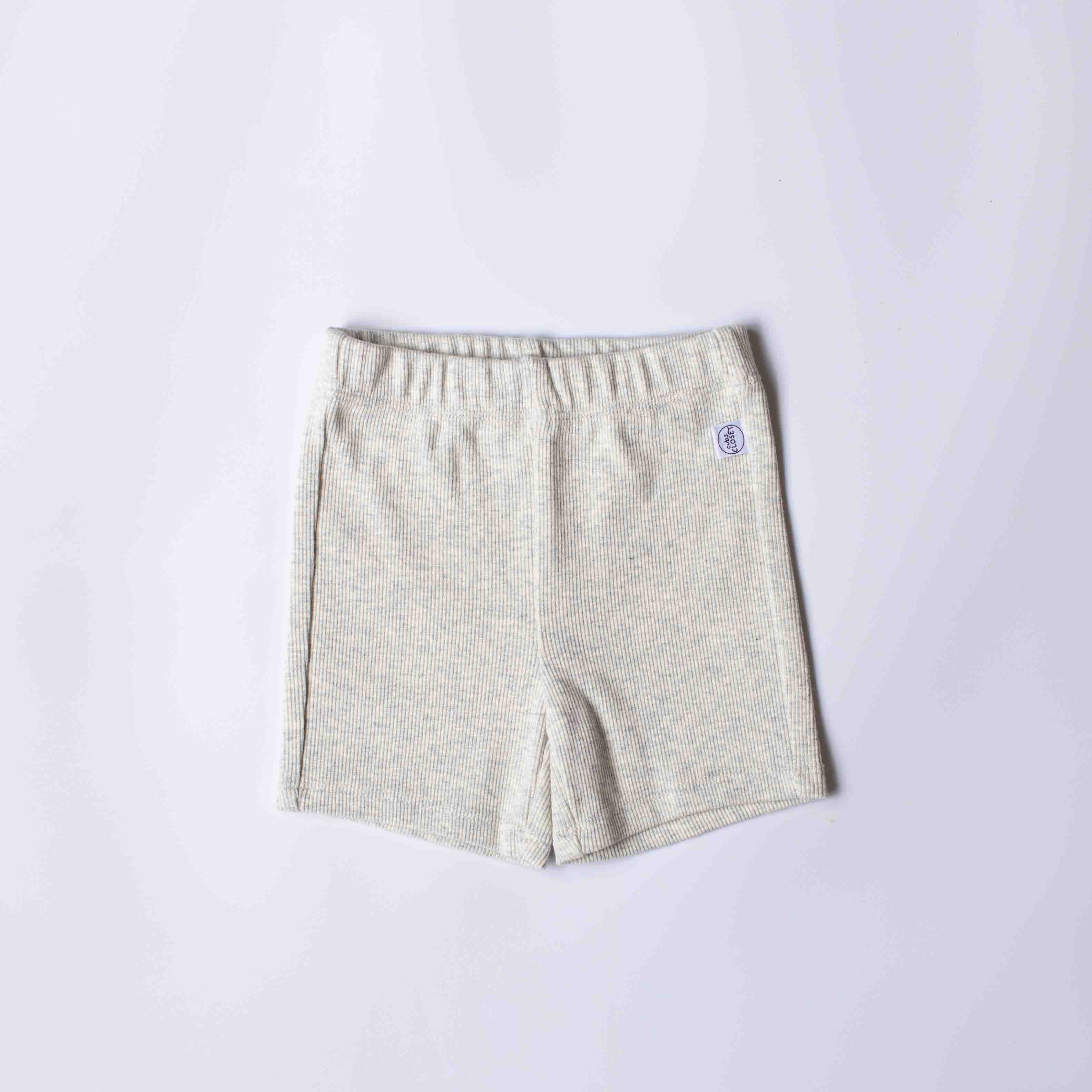 A pair of light beige heathered shorts with an elastic waistband, laid flat on a light gray background.