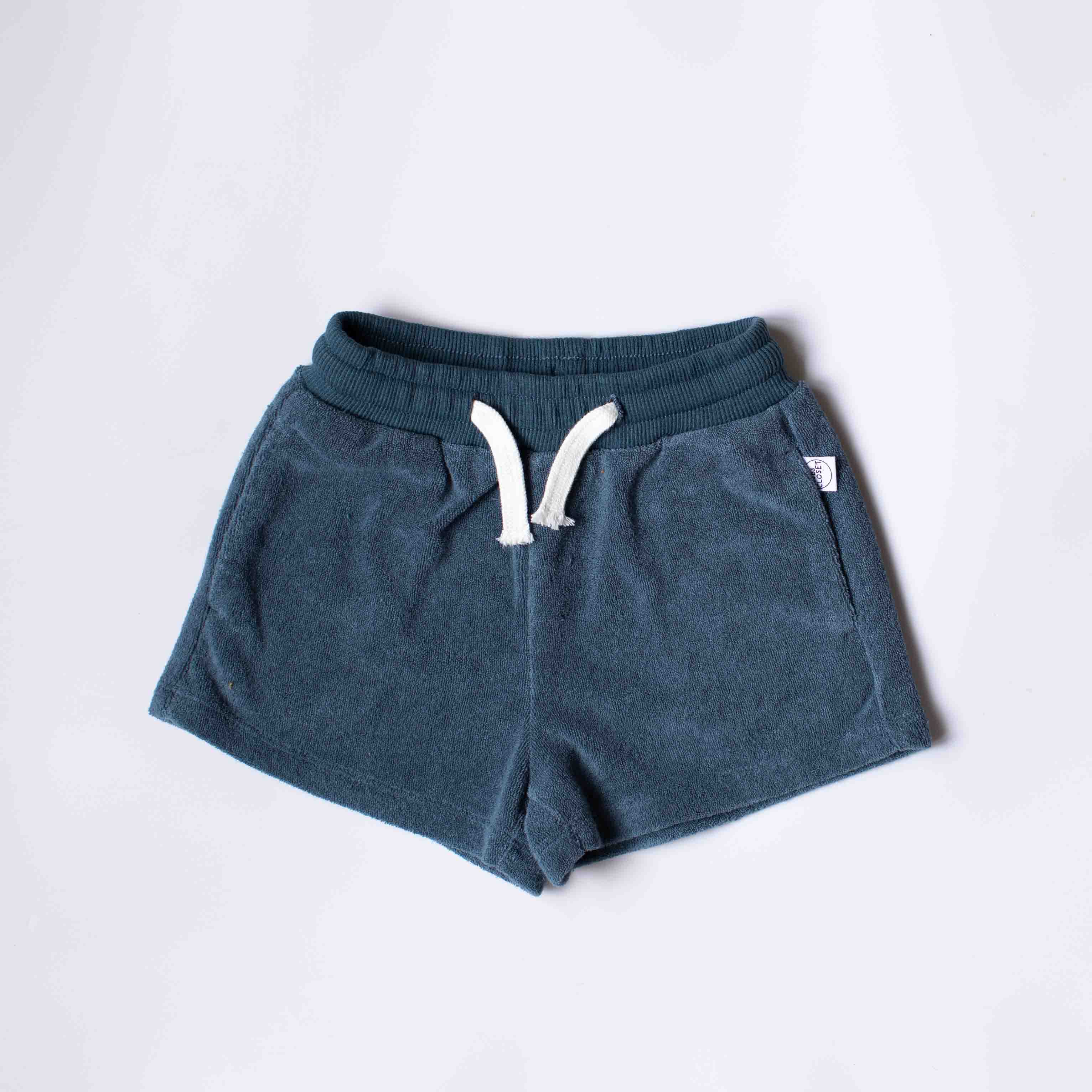 A pair of dark teal blue sweat shorts with a white drawstring, laid flat on a light gray background.