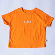 An orange short-sleeve t-shirt with the word 'cubs' embroidered in white across the chest, laid flat on a light gray background.