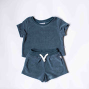 A toddler's two-piece lounge set consisting of a short-sleeve crewneck t-shirt and matching drawstring shorts in a heathered slate blue color, laid flat on a white background.