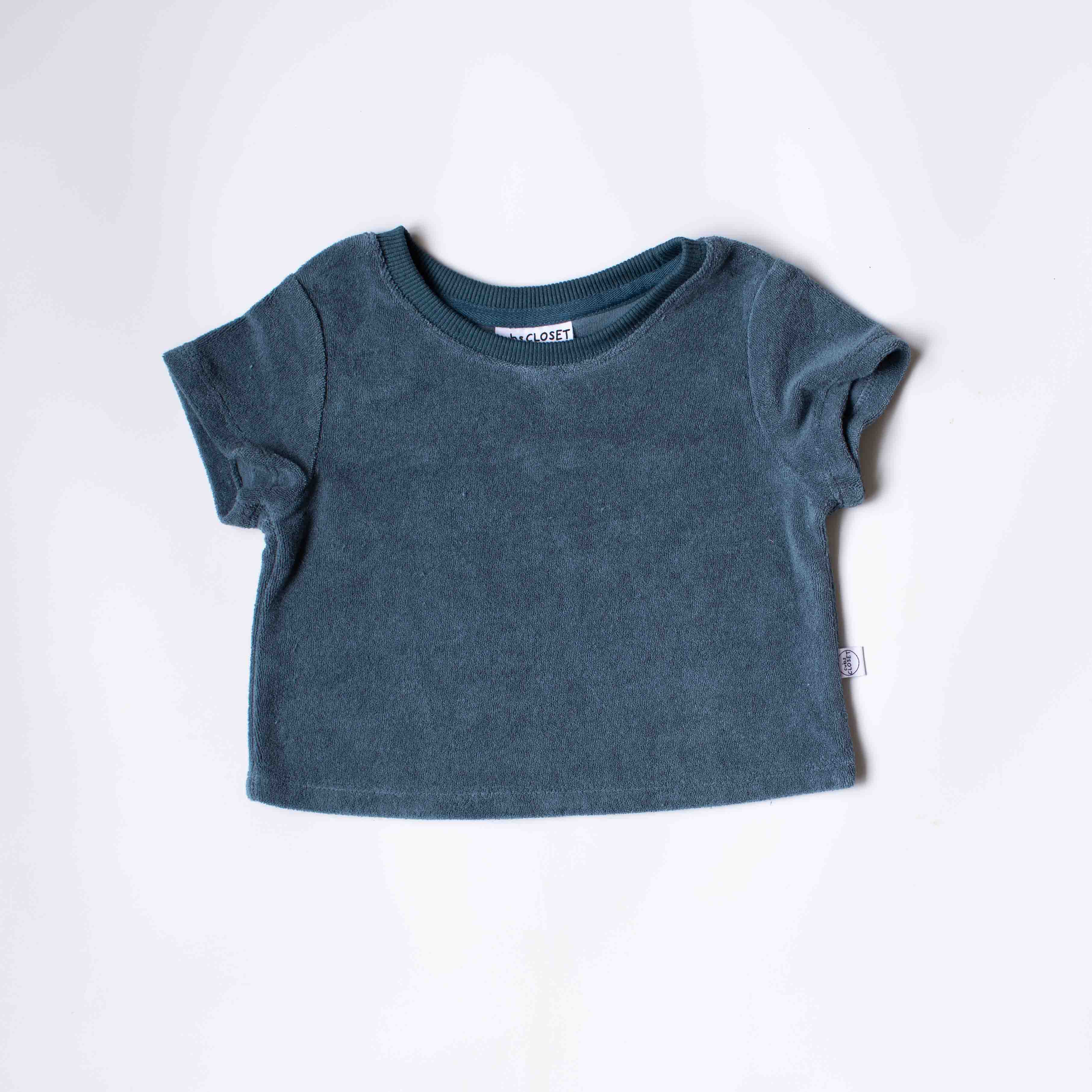 A short-sleeve crewneck baby tee in a muted slate blue color, laid flat on a white background.