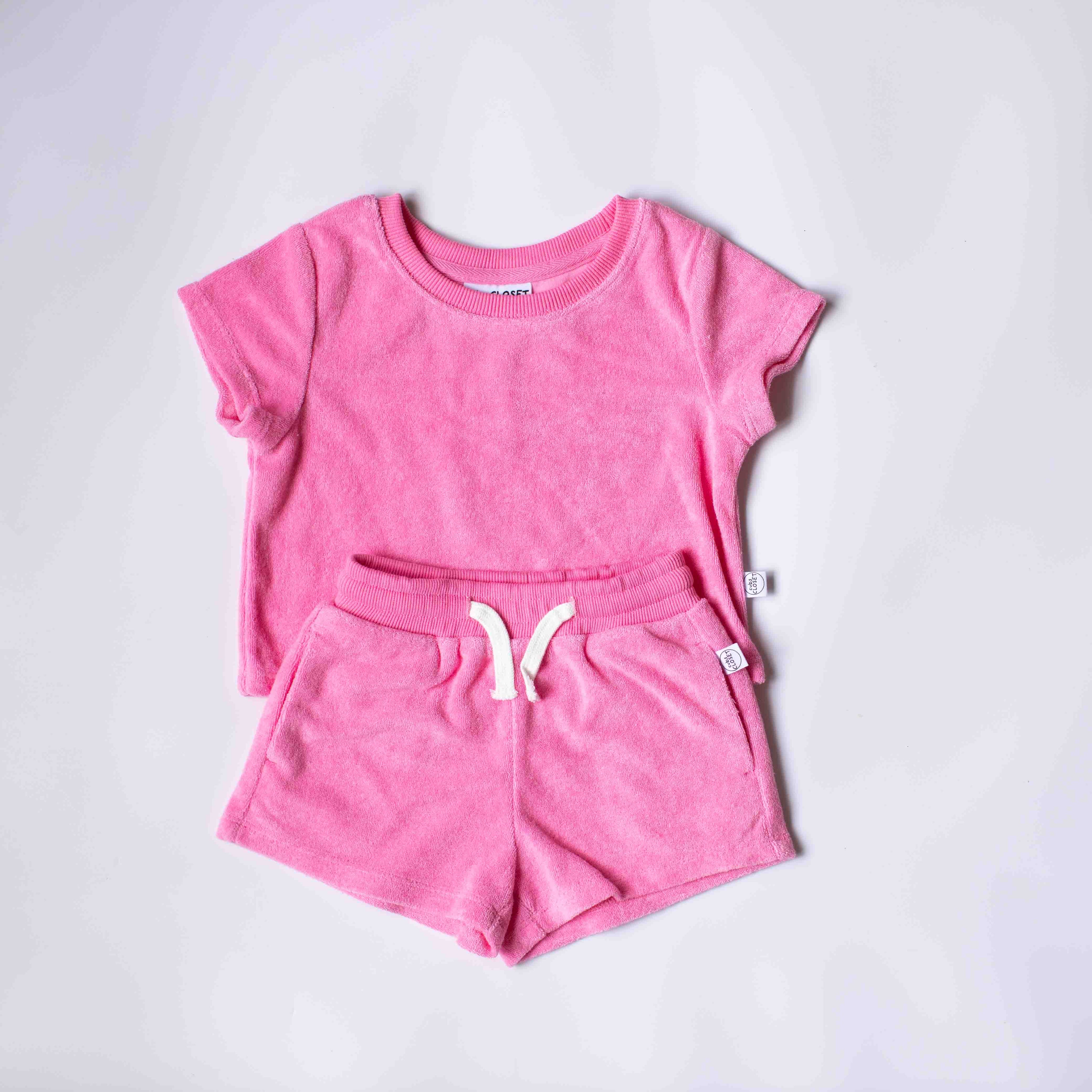 A two-piece kids' loungewear set in a heathered pink fabric, featuring a short-sleeve crewneck t-shirt and matching drawstring shorts, laid flat on a light gray background.