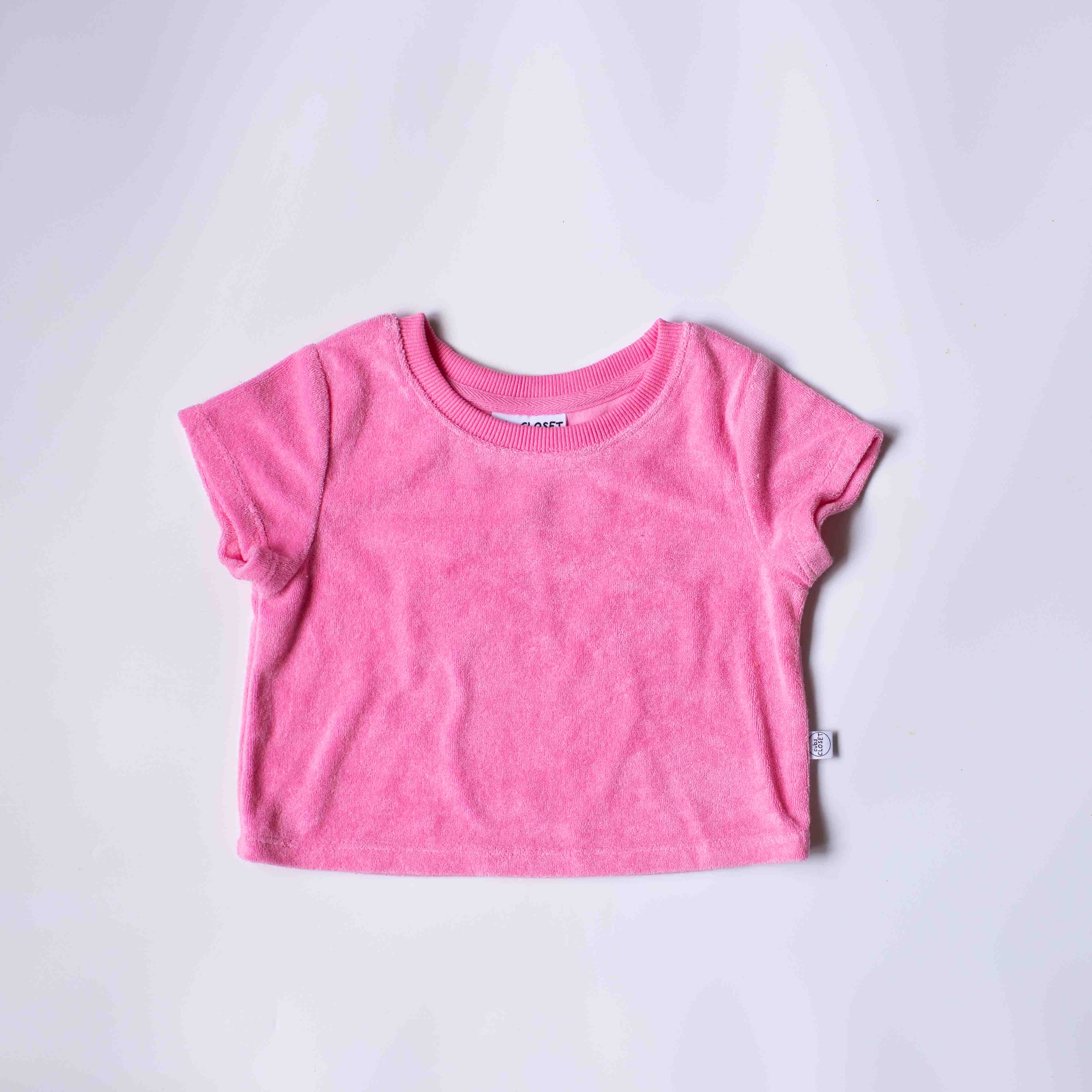A pink short-sleeve baby t-shirt laid flat on a light gray background.