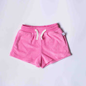 Pink fleece shorts with a white drawstring, laid flat on a light gray background.